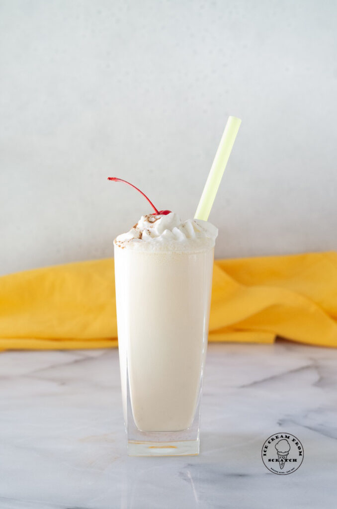 close up of banana milkshake with whipped cream and a cherry on top