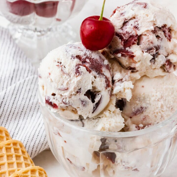 cherry vanilla ice cream in a bowl topped with a cherry