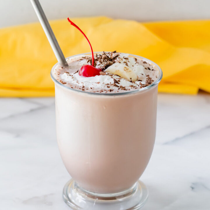 chocolate banana milkshake in a glass with a metal straw