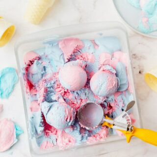 scoops of cotton candy ice cream in a glass pan with a scooper