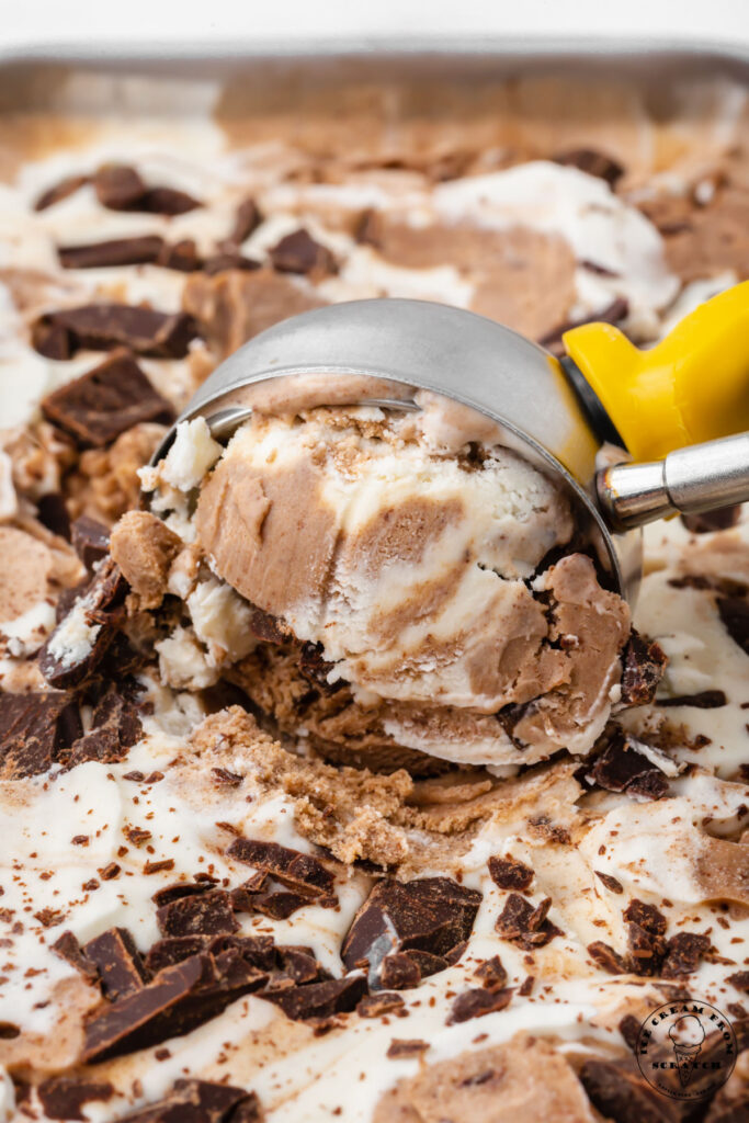 french silk ice cream topped with chocolate chunks being scooped with a silver and yellow ice cream scoop.