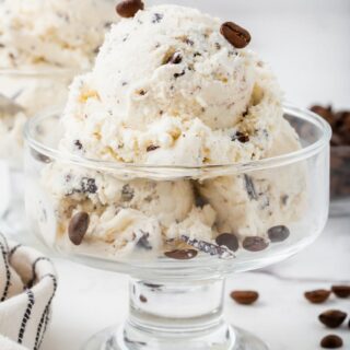 a glass ice cream dish filled with java chip ice cream, topped with coffee beans