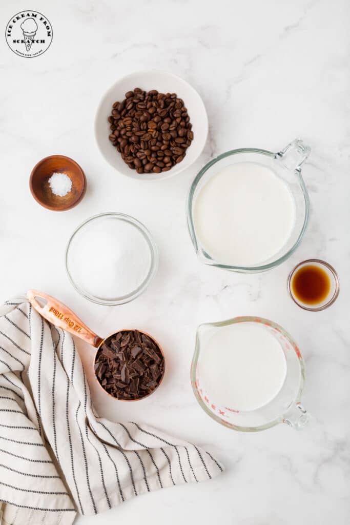 ingredients needed for java chip ice cream, each in separate dishes on a marble countertop with a black and white striped tea towel.