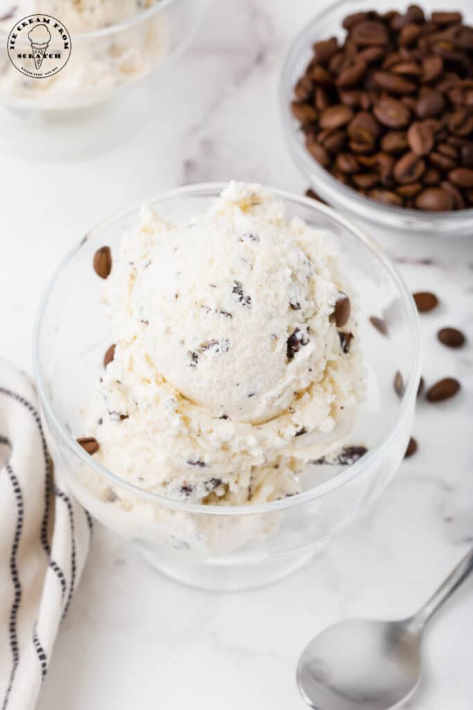 a glass dish of java chip ice cream next to a bowl of coffee beans.