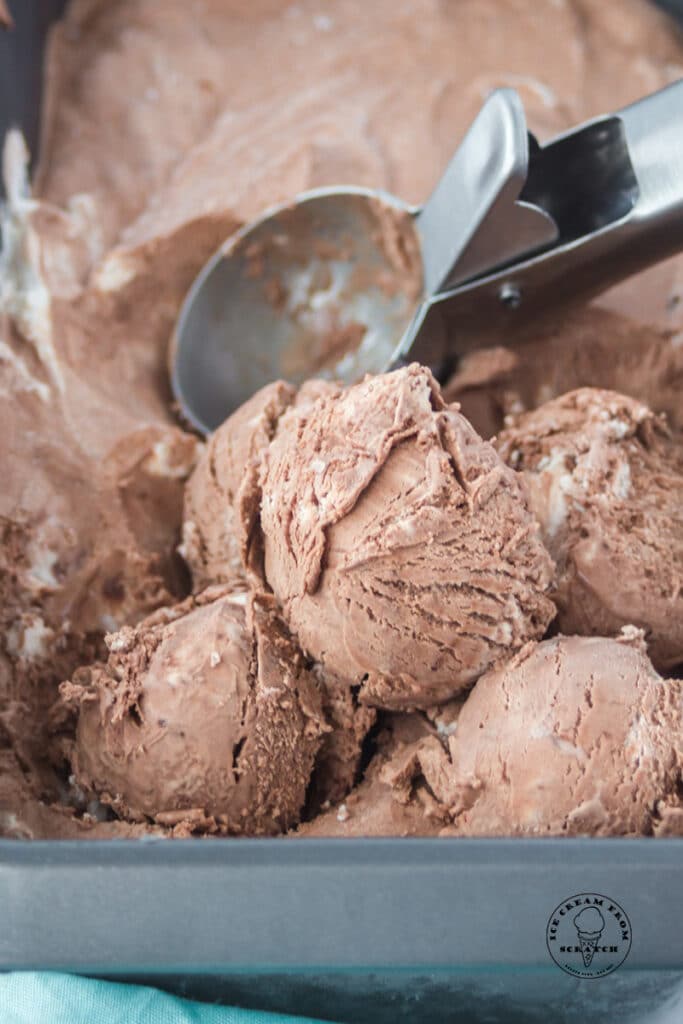 a pan of chocolate ice cream being scooped with a silver ice cream scoop