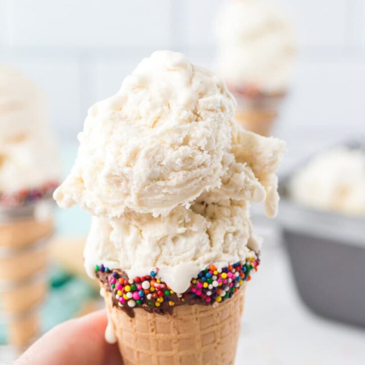 a sugar cone dipped in chocolate and rainbow sprinkles, filled with vanilla ice cream.