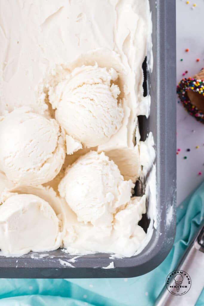 a pan of vanilla ice cream with three scoops on top.