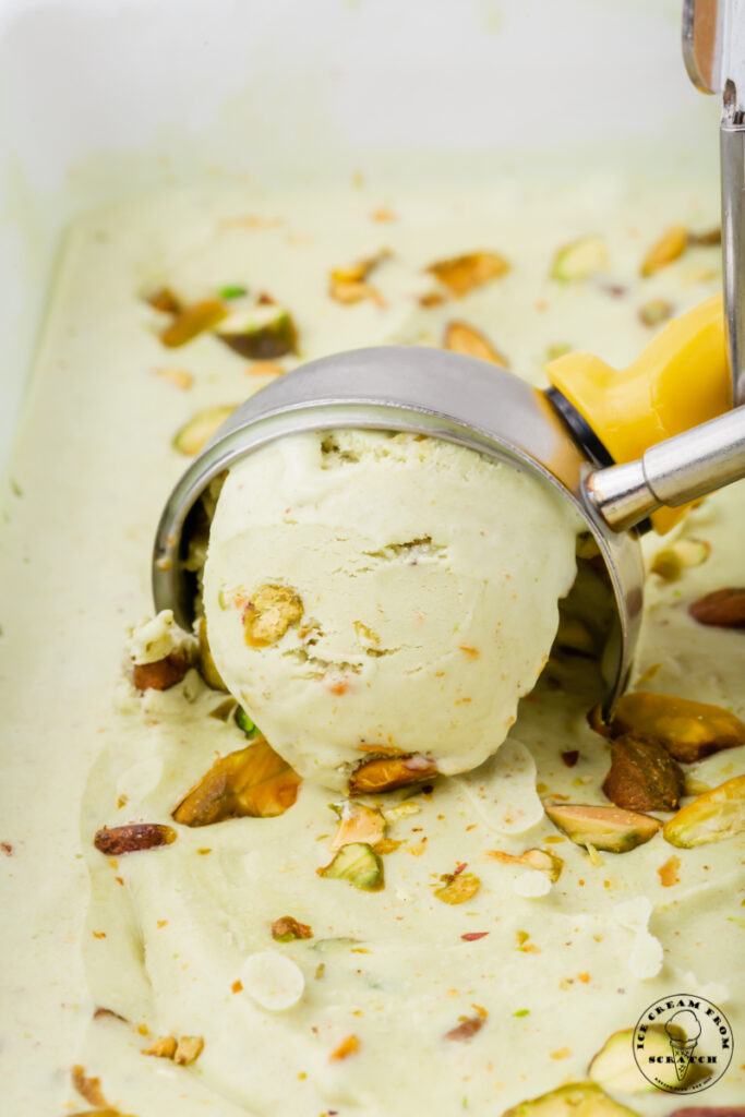 pistachio ice cream being scooped with a silver ice cream scooper.