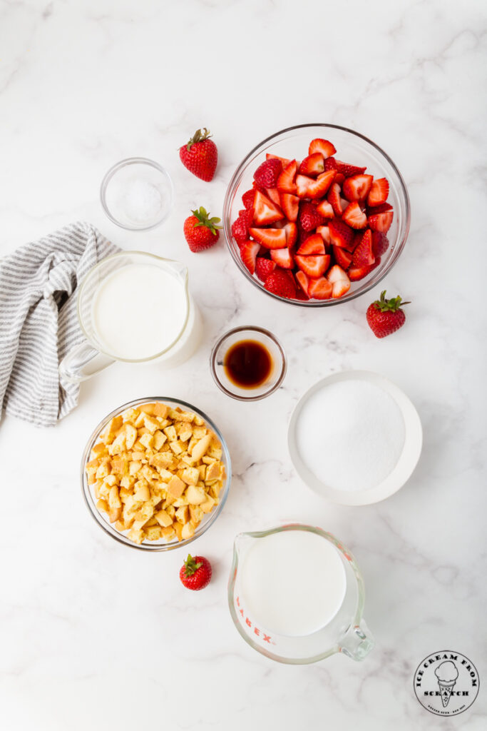 Ingredients needed for strawberry shortcake ice cream, each in separate bowls on a marble countertop