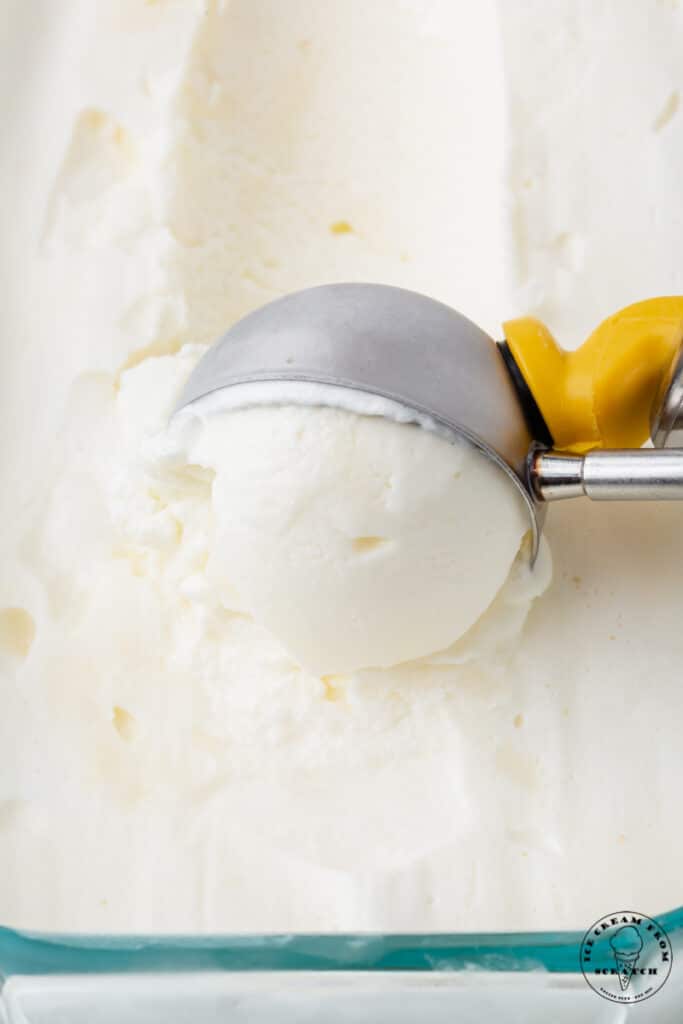 a vintage style metal ice cream scoop, scooping into creamy white, sweet cream ice cream.