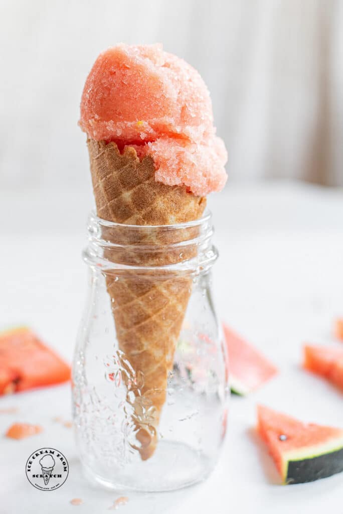 a scoop of watermelon sorbet in an ice cream cone, in a jar