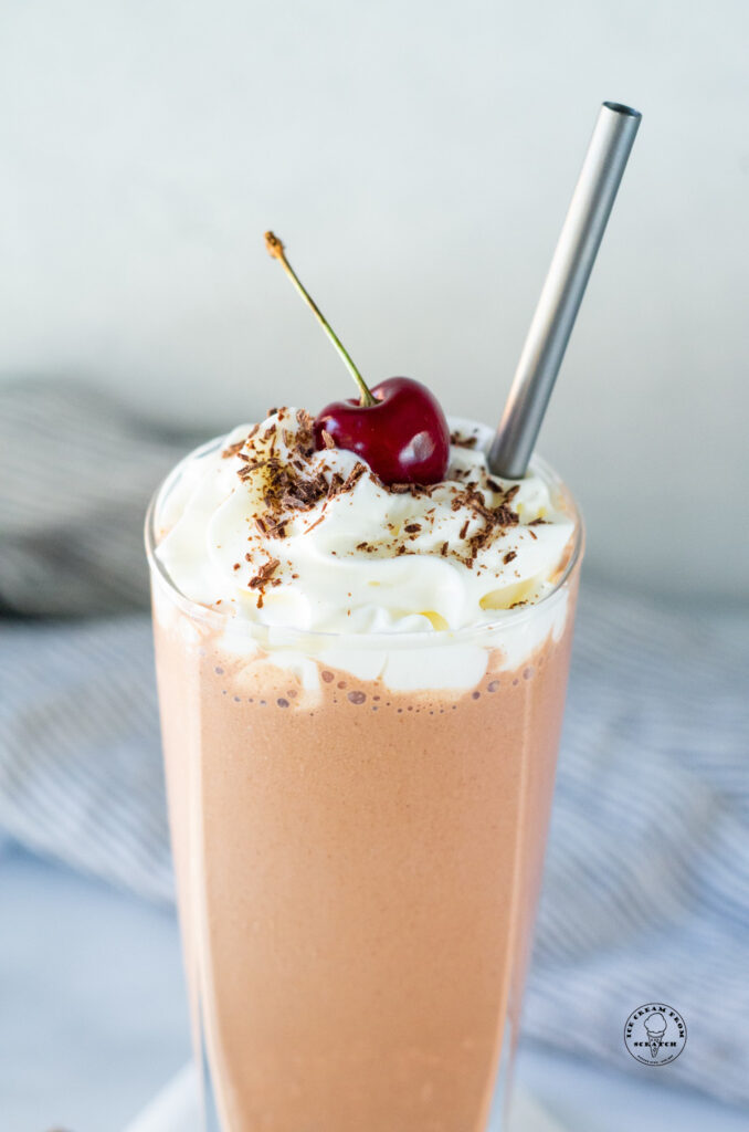close up of top of a chocolate peanut butter milkshake with a cherry on top