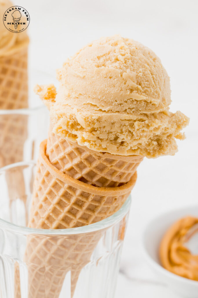two sugar cones held upright inside of a glass, topped with a scoop of homemade peanut butter ice cream