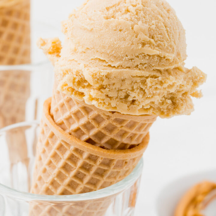 two sugar cones held upright inside of a glass, topped with a scoop of homemade peanut butter ice cream