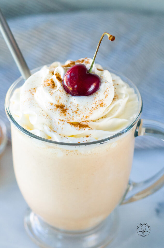 close up of a peanut butter milkshake with a cherry on top