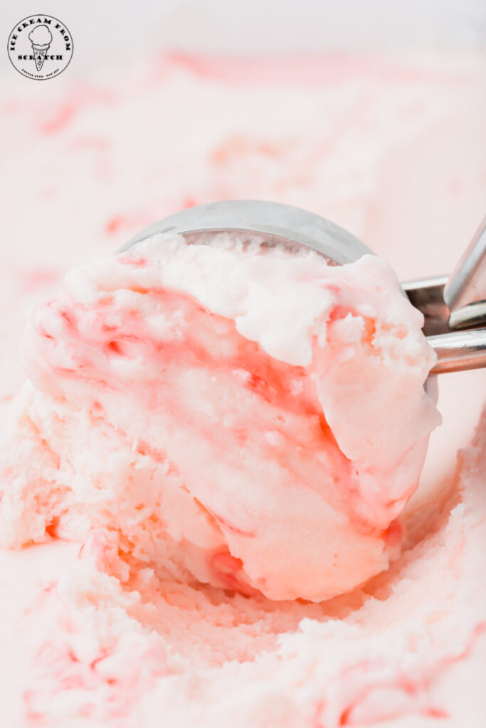 a metal ice cream scoop making a scoop of peppermint stick ice cream.