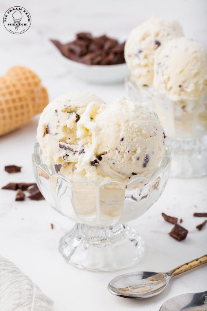 a footed glass dessert dish is filled with scoops of homemade chocolate chip ice cream
