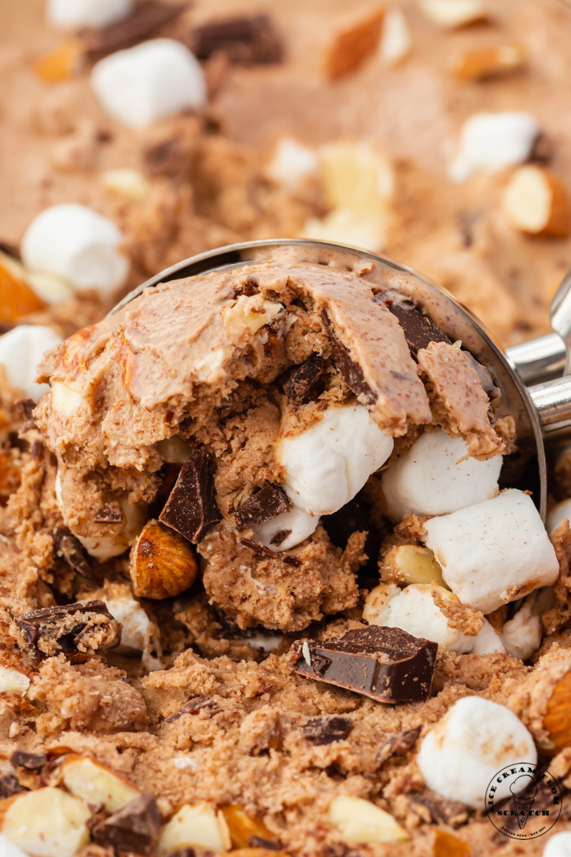 homemade rocky road ice cream packed with chocolate, almonds, and marshmallows is being scooped with a metal ice cream scoop
