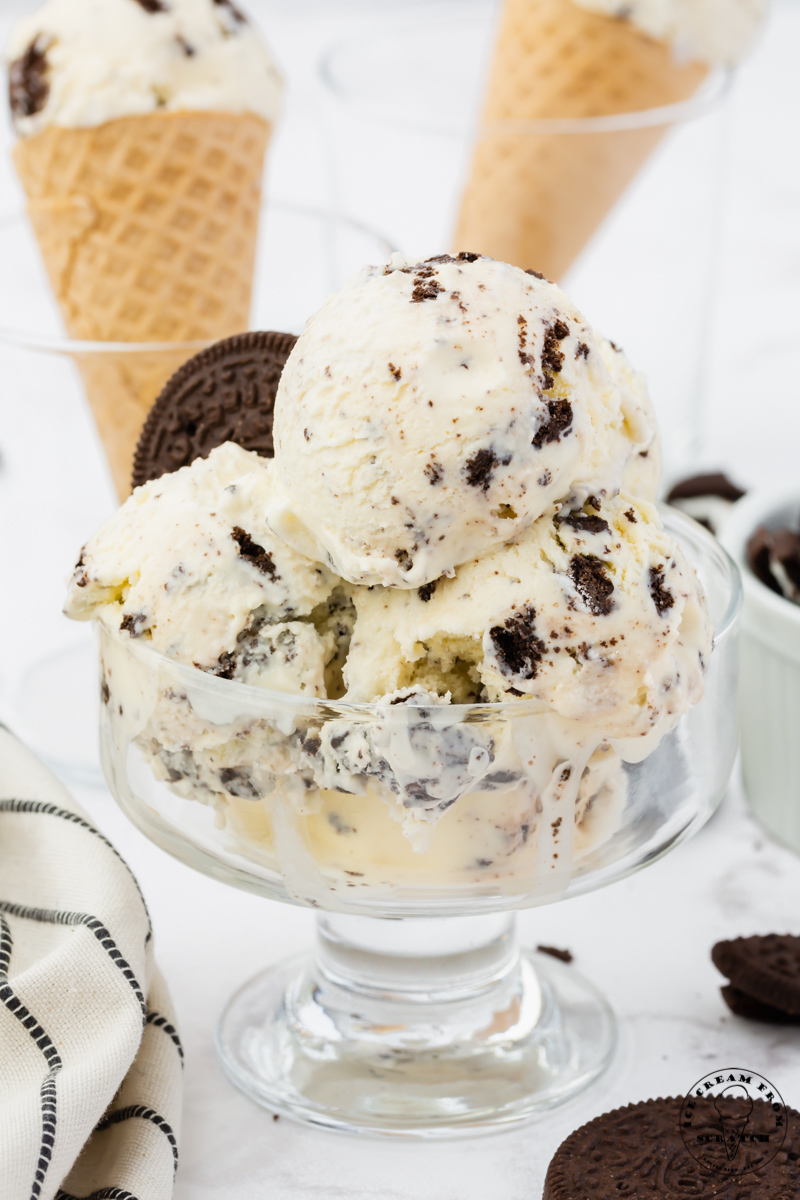 a footed glass dish filled with scoops of oreo ice cream, garnished with oreo cookies.