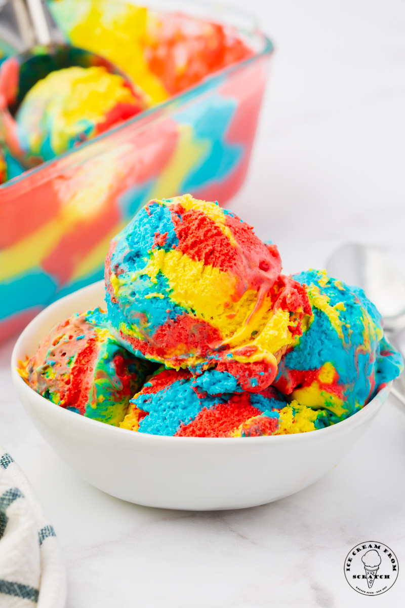 a bowl filled with scoops of superman ice cream. In the background is a glass container that the ice cream came from.