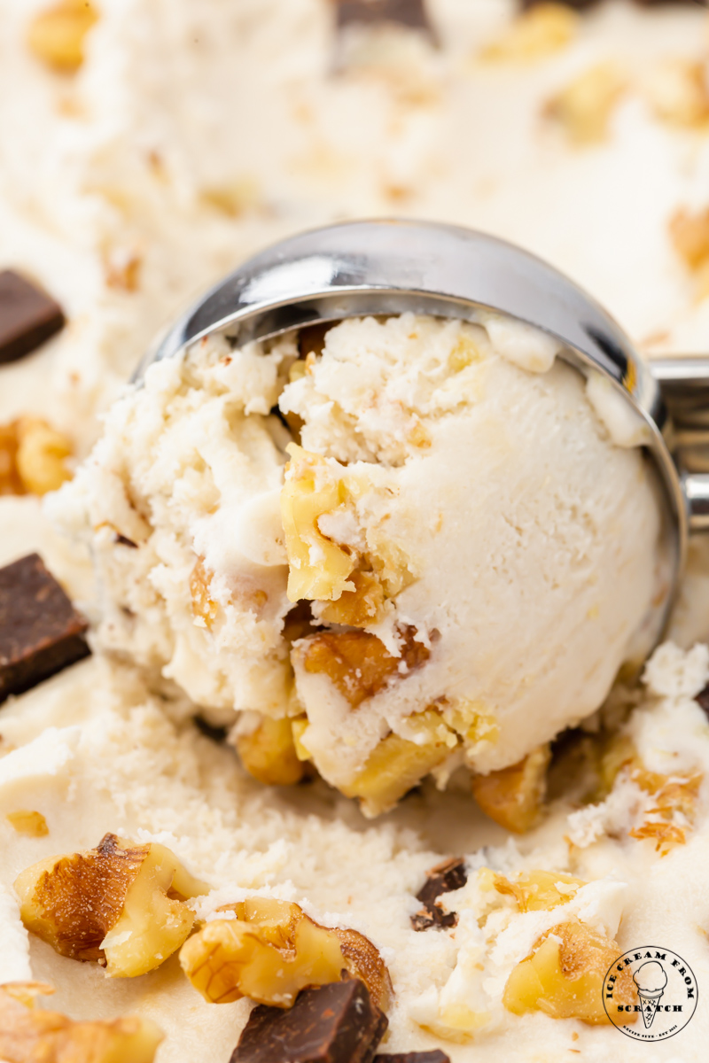 Closeup view of a metal ice cream scoop creating a scoop of homemade chunky monkey ice cream