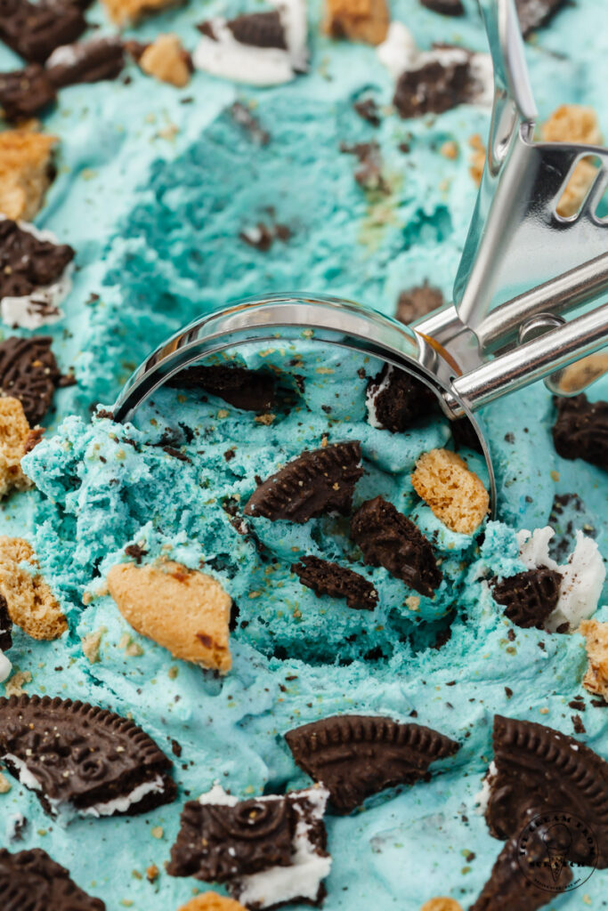 closeup view of a pan of homemade cookie monster ice cream, being scooped with a metal ice cream scoop
