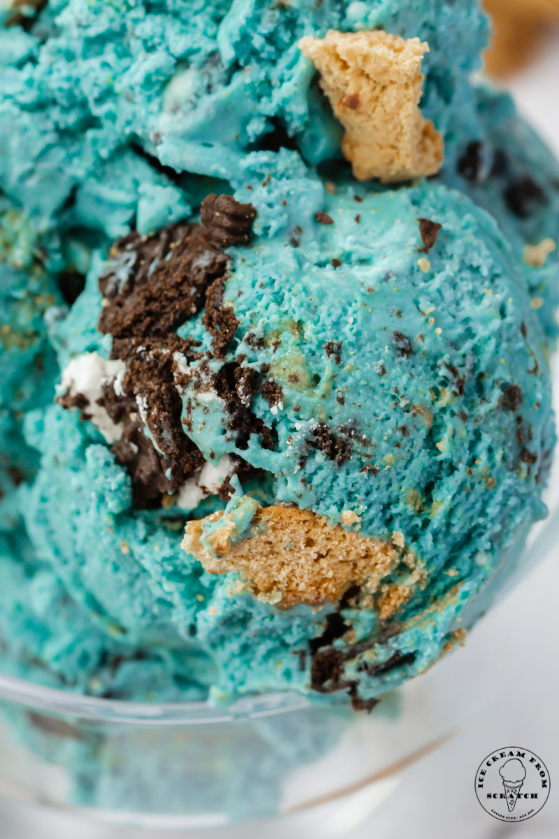 closeup view of homemade cookie monster ice cream showing the texture of the oreo and chocolate chip cookies inside of blue ice cream base.