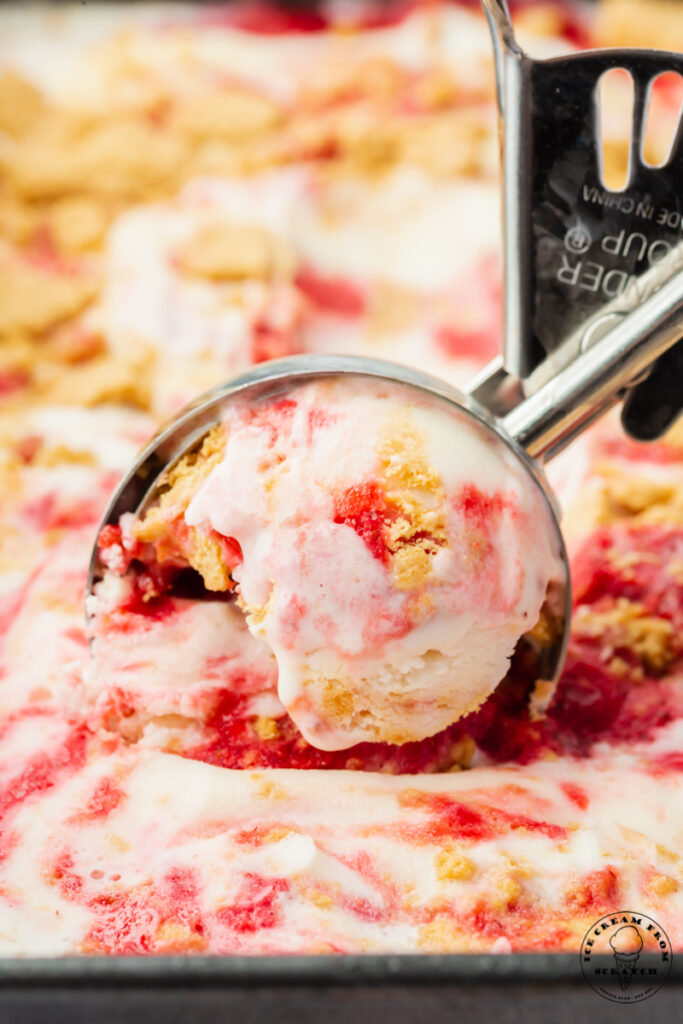 closeup view of strawberry cheesecake ice cream scooped with an ice cream scoop.