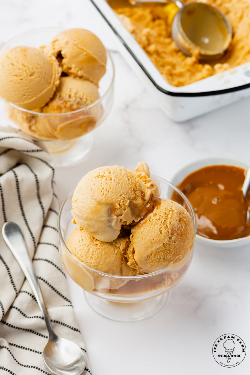 two bowls of scooped homemade dulce de leche ice cream, next to a bowl of dark caramel.