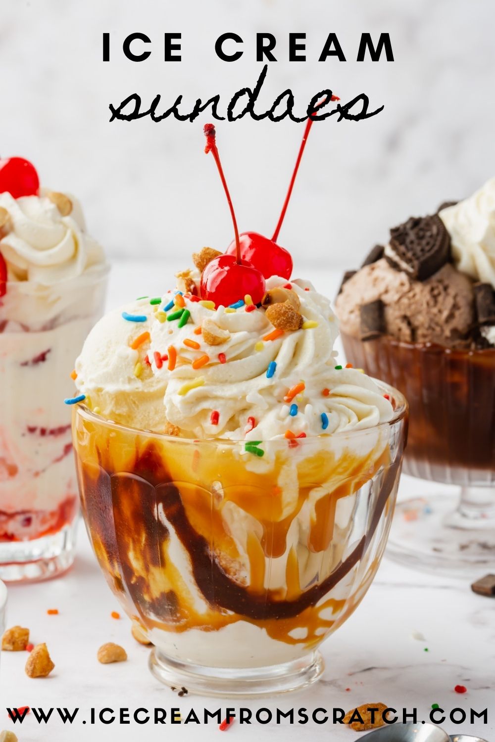 A glass bowl filled with a chocolate caramel ice cream sundae, topped with whipped cream, sprinkles, and two maraschino cherries. More ice cream sundaes of different varieties are in the background.
