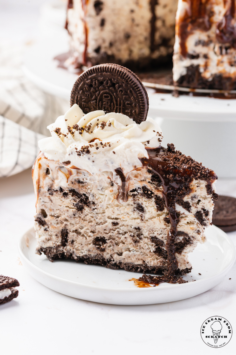 a slice of scratch made oreo ice cream cake, viewed from the side, on a small white plate.