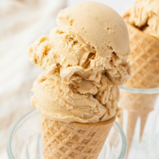 a sugar cone topped with scoops of tan colored butterscotch ice cream.