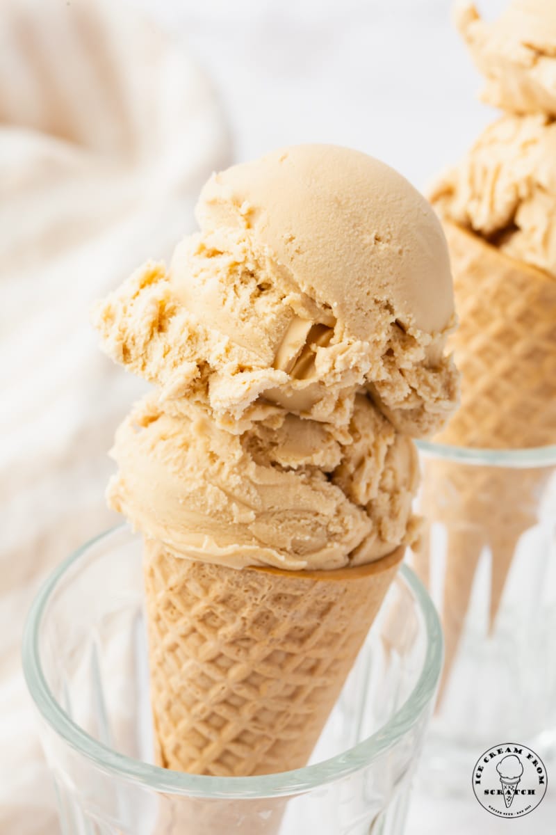 a sugar cone topped with scoops of tan colored butterscotch ice cream.