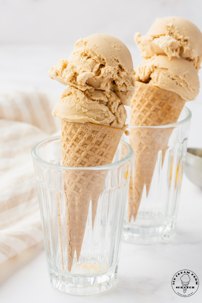 Two juice glasses, each holding a butterscotch ice cream cone.