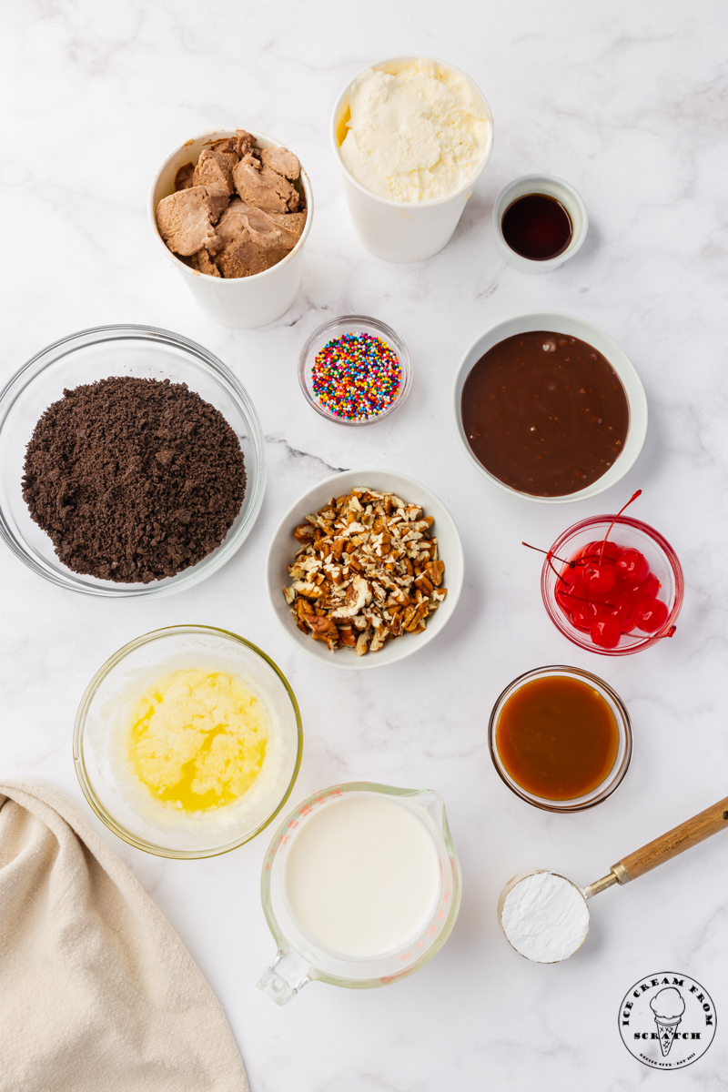 The ingredients needed to make an ice cream pie, all measured out into small bowls on a marble countertop, viewed from above