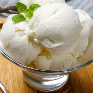 side view of no churn vanilla ice cream in a clear bowl with mint on top