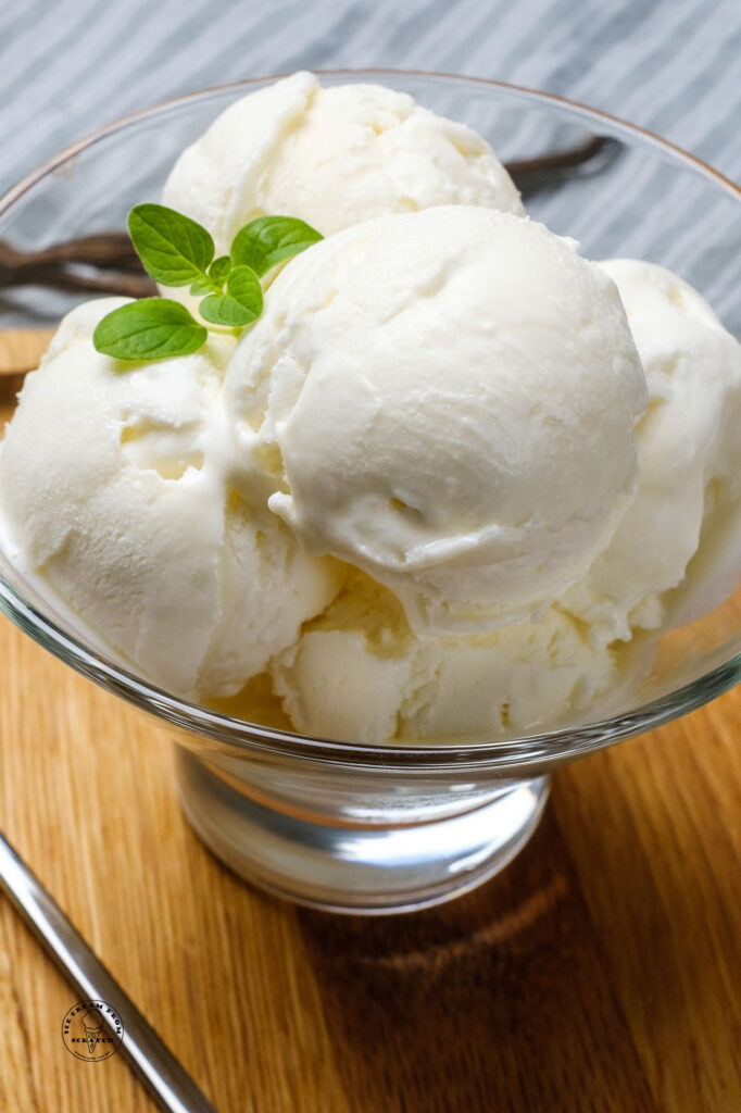 side view of no churn vanilla ice cream in a clear bowl with mint on top