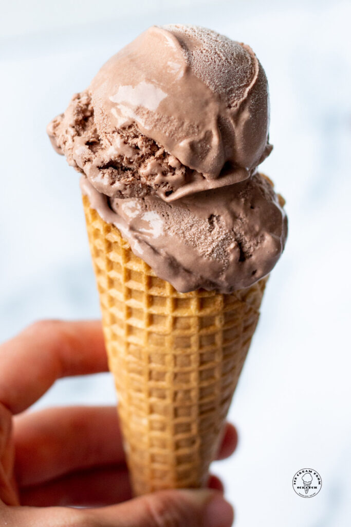 hand holding a cone filled with scoops of no churn chocolate ice cream