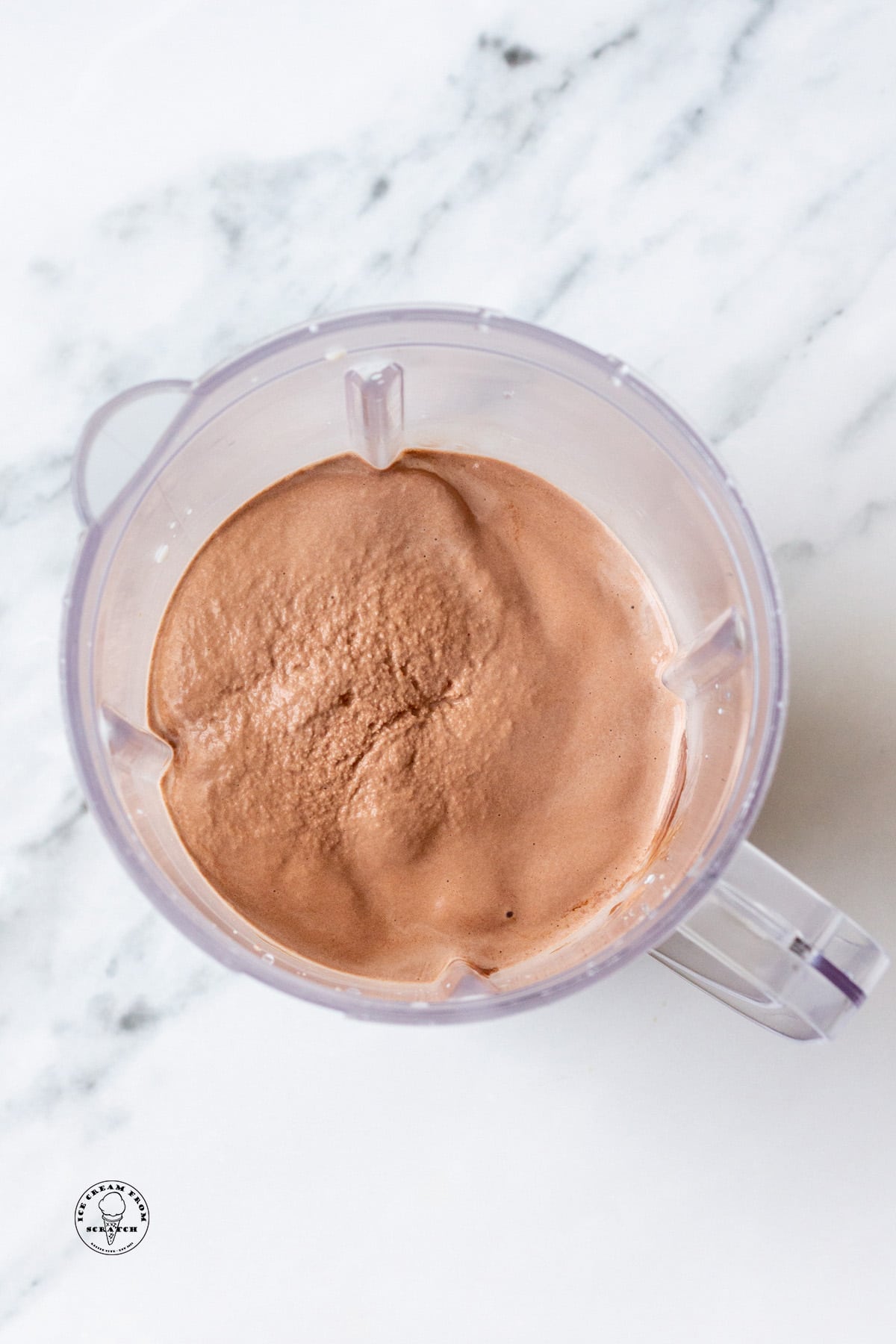 A blended chocolate milkshake in a blender container, viewed from above