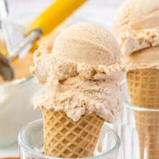 a sugar cone with two scoops of homemade cinnamon ice cream, propped up in a glass.