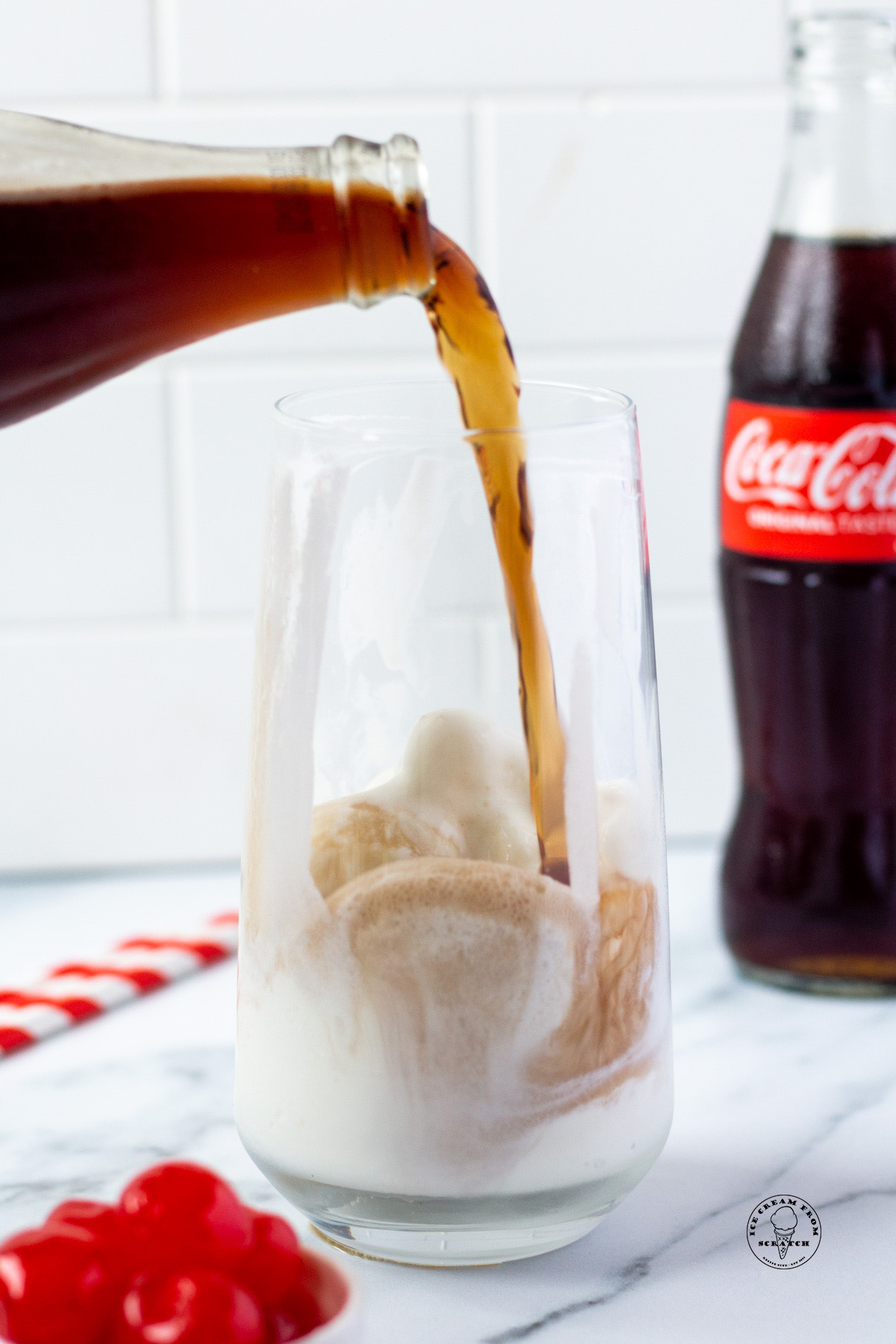 A bottle of soda being poured into a glass of ice cream to make a float