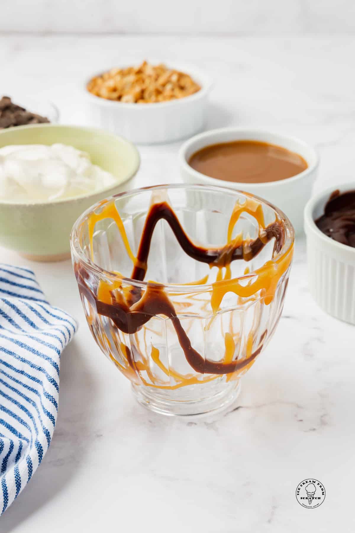 a sundae glass with swirls of chocolate and caramel sauce swirled inside. 