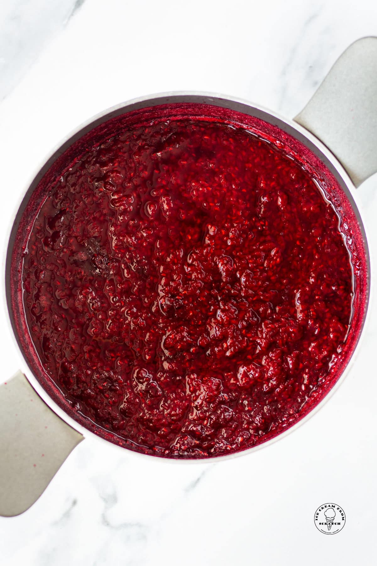 a metal saucepan filled with cooked raspberry compote