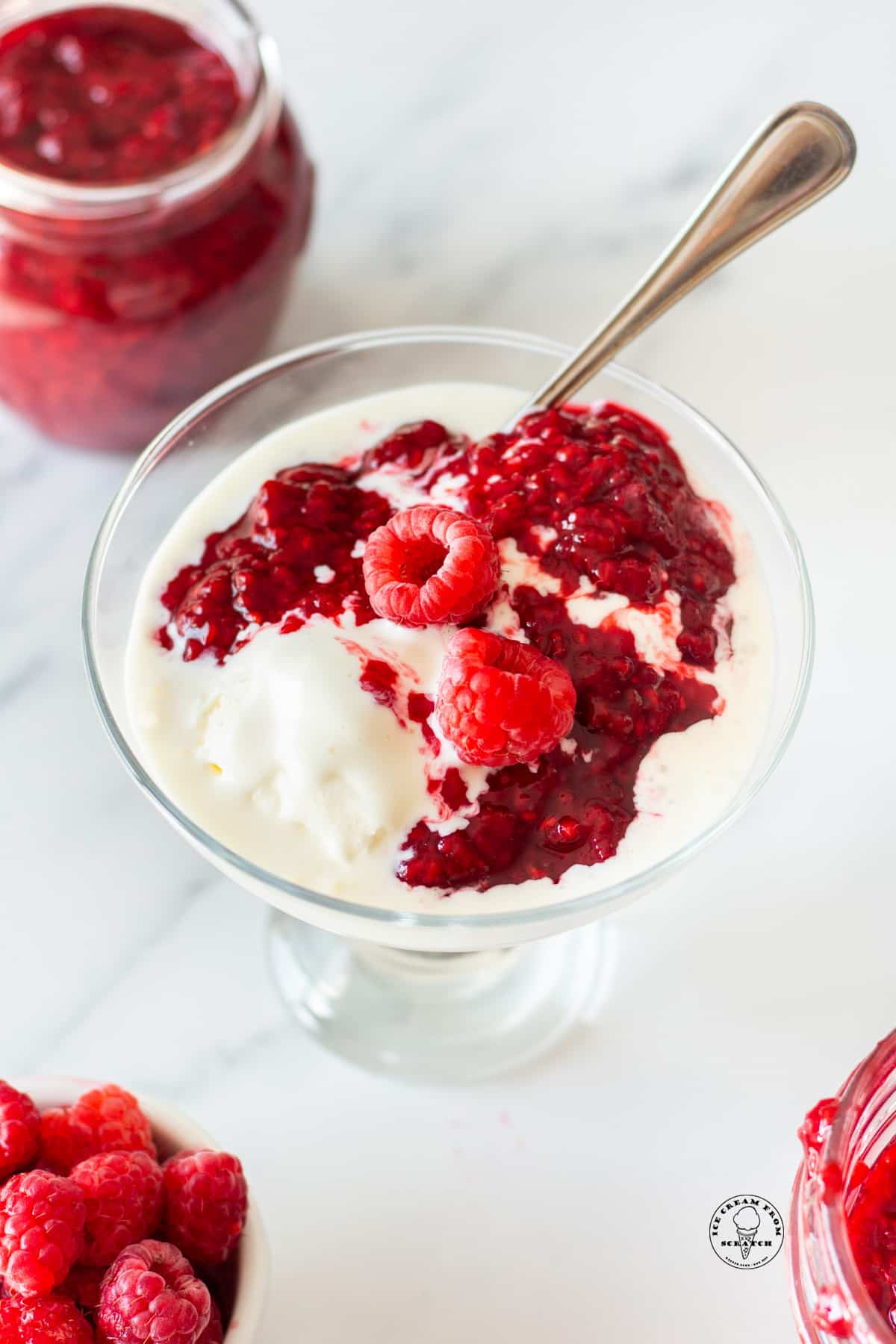 a dish of ice cream topped with warm raspberry compote and fresh berries