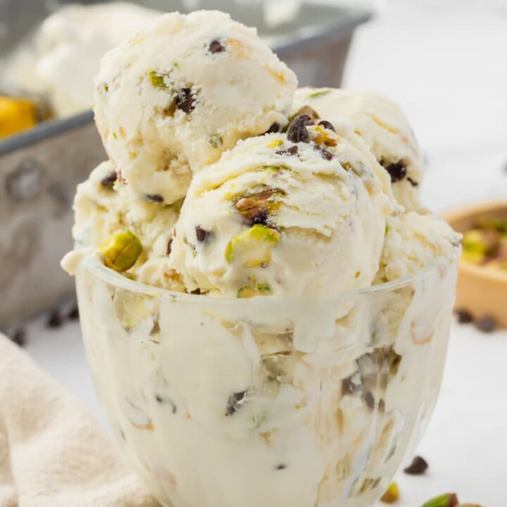 cannoli ice cream with chopped pistachios and chocolate chips in a glass dessert dish.