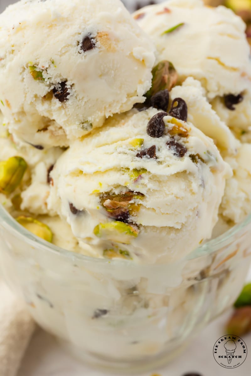 Scoops of cannoli ice cream with pistachios in a glass bowl, close up image.