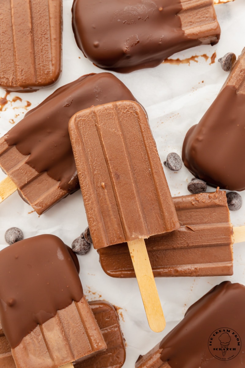 Chocolate ice cream bars, some dipped in chocolate coating, arranged on a tray, viewed from overhead.