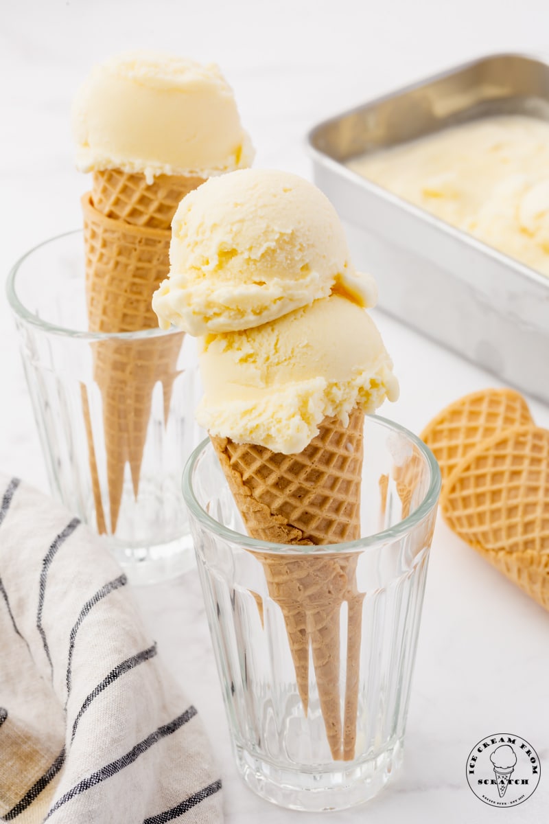 Two juice glasses holding up ice cream cones topped with homemade mascarpone ice cream.