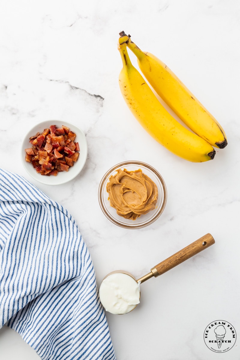 Bananas, chopped bacon, peanut butter, and sour cream on a counter, measured into small bowls.