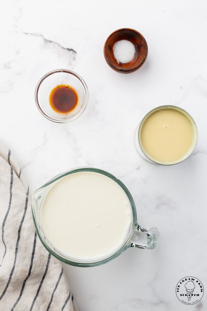 the four ingredients needed to make rolled ice cream, in separate bowls on the counter, viewed from overhead.